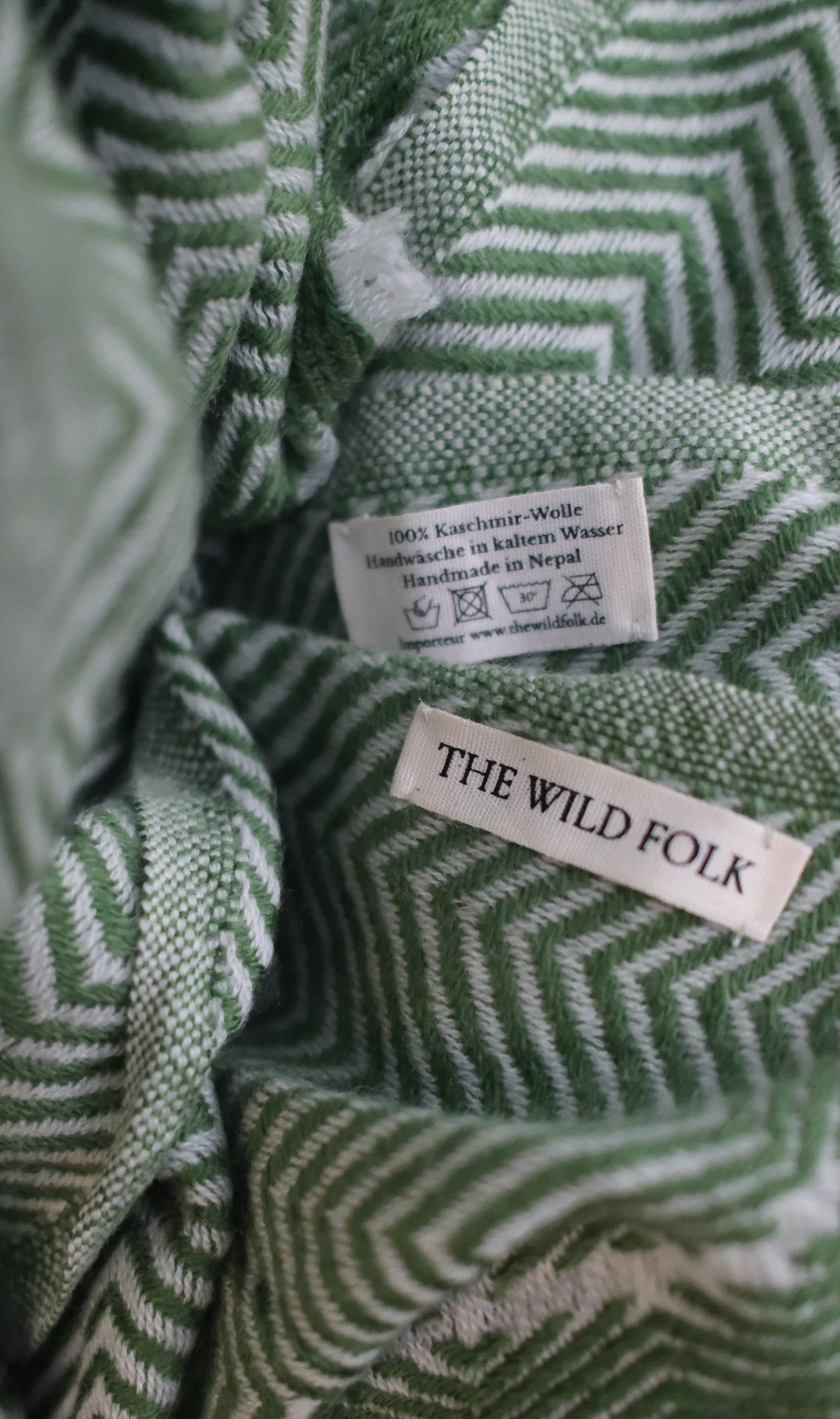 Detailaufnahme des Fischgrat Musters und des Brand-Labels und der Waschanleitung.