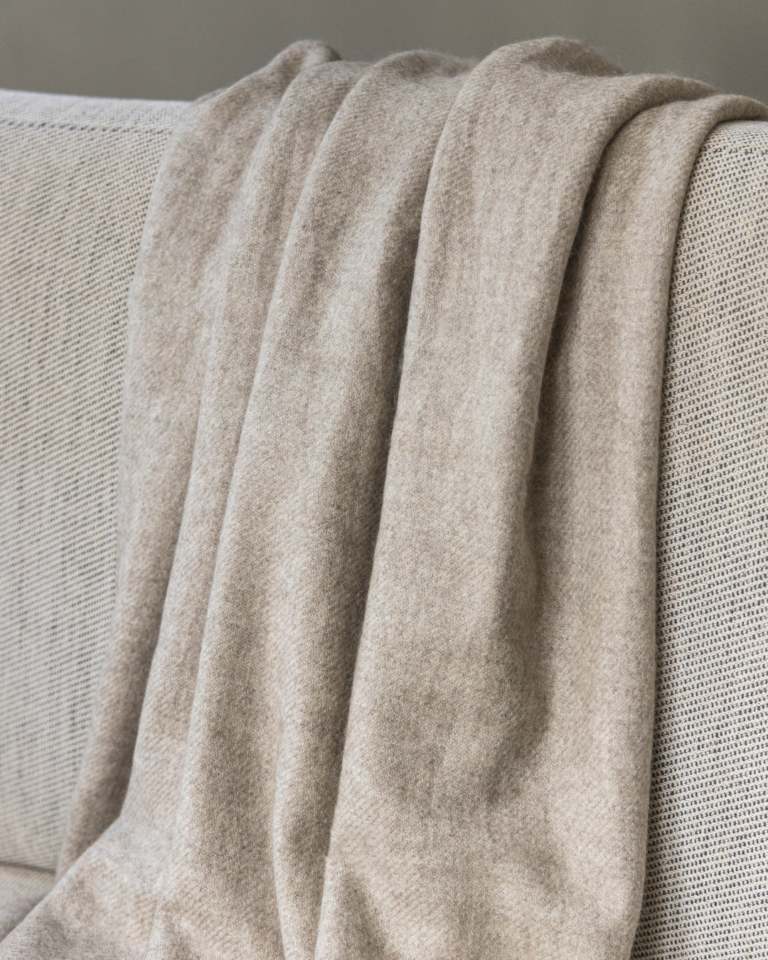 Yakwolle-Decke in Beige liegt über einem Sofa.