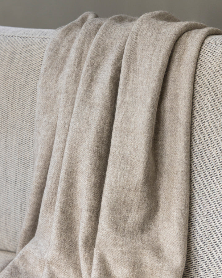 Yakwolle-Decke in Beige liegt über einem Sofa.