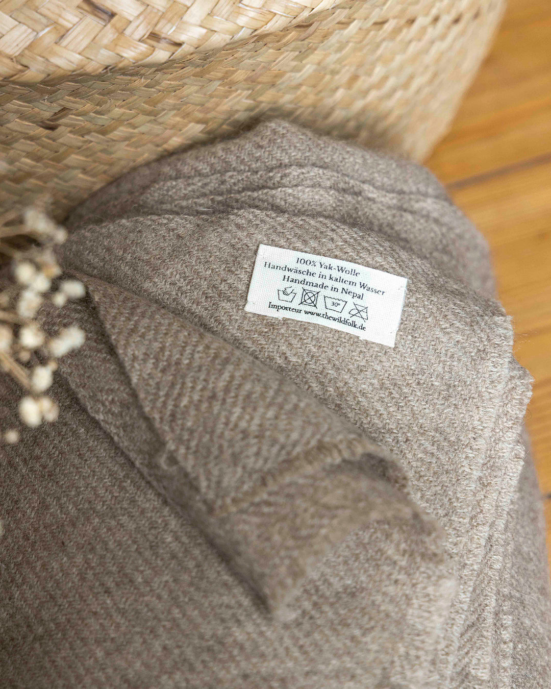 Detailaufnahme der Waschanleitung an einer mittel-Braunen Decke aus Yakwolle.