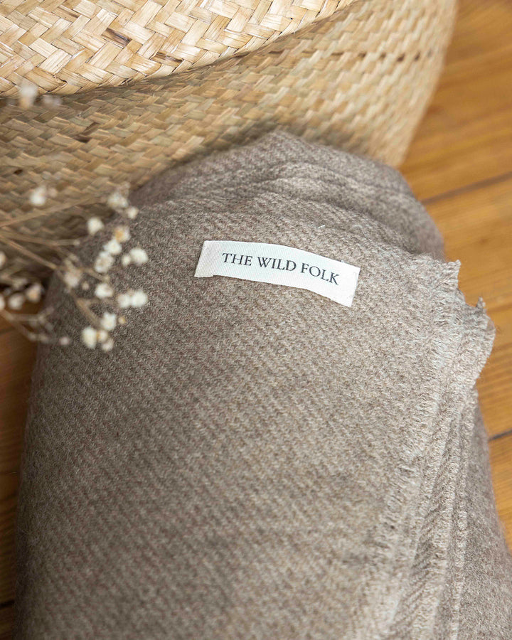 Yakdecke aus yakwolle zusammengerollt mit dem Label der Brand TheWildFolk sichtbar.