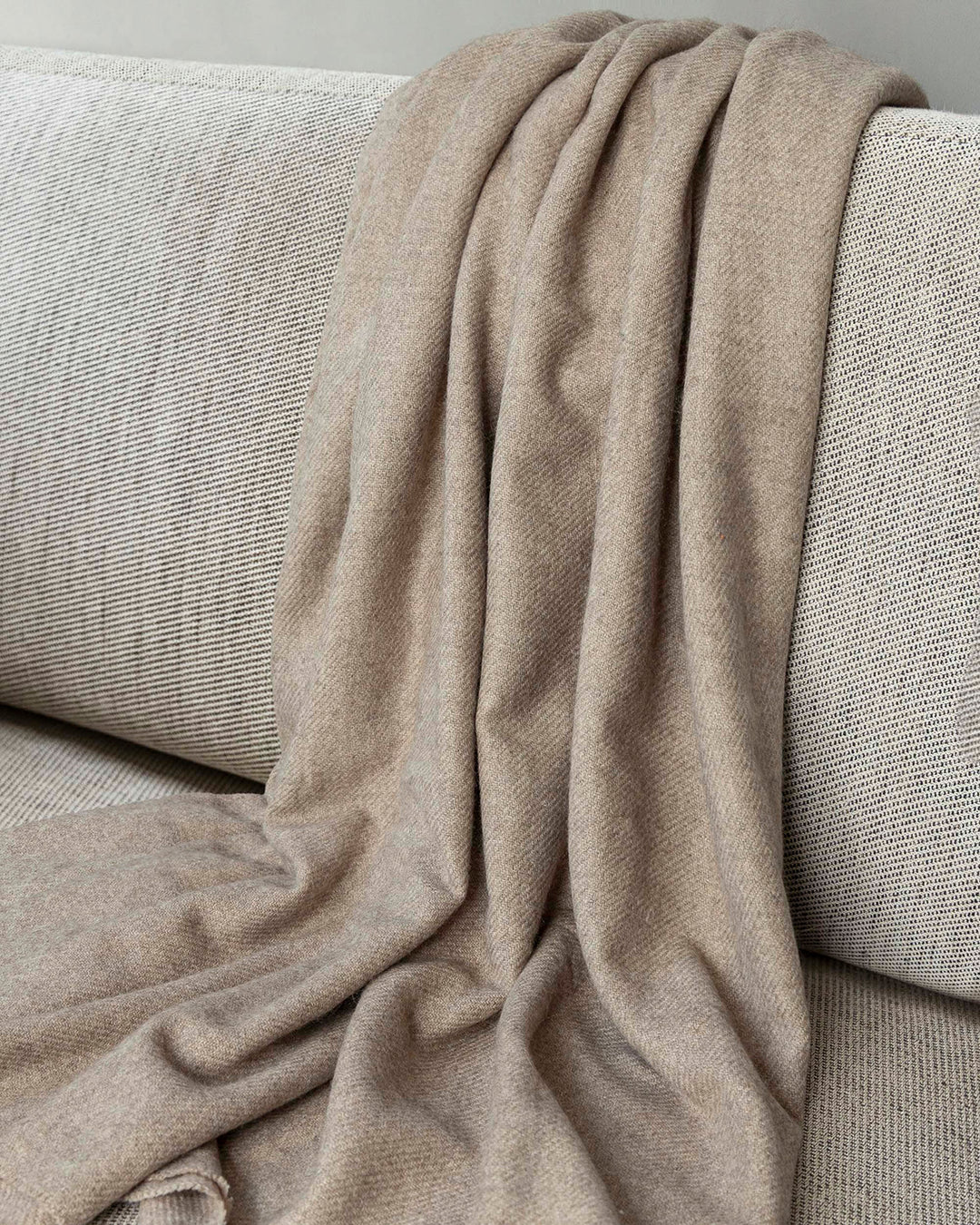 Braune Decke aus Yakwolle liegt auf einem Sofa.