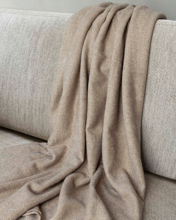 Braune Decke aus Yakwolle liegt auf einem Sofa.
