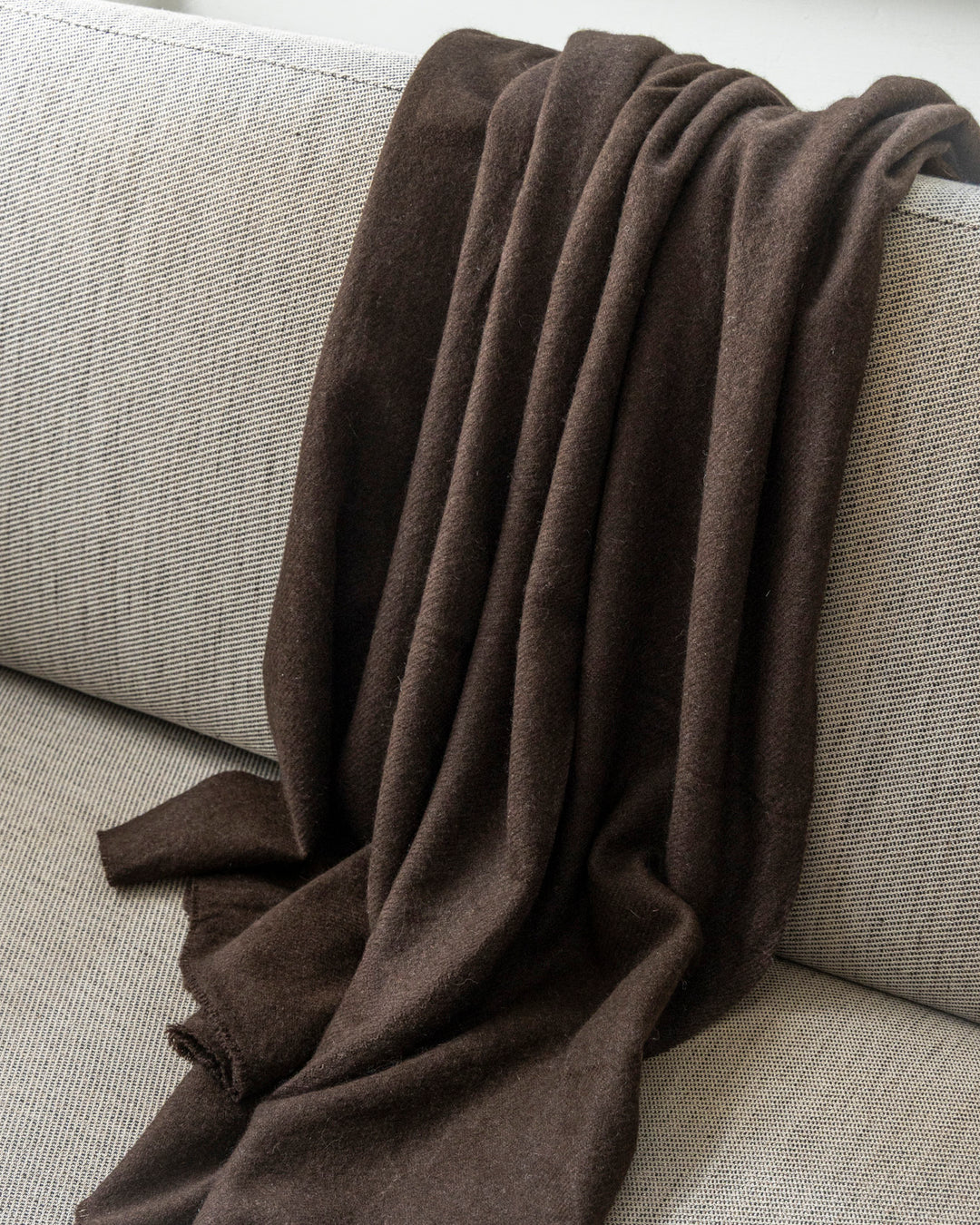 Decke aus Dunkelbrauner Yakwolle liegt auf einem Sofa.