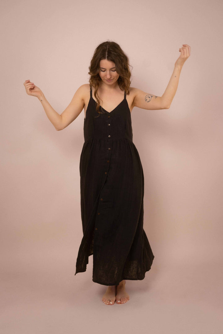 Ein elegantes schwarzes Maxikleid mit Knöpfen. das lange Trägerkleid hat einen V-Ausschnitt und ist minimalistisch gehalten. Vintagekleid. 