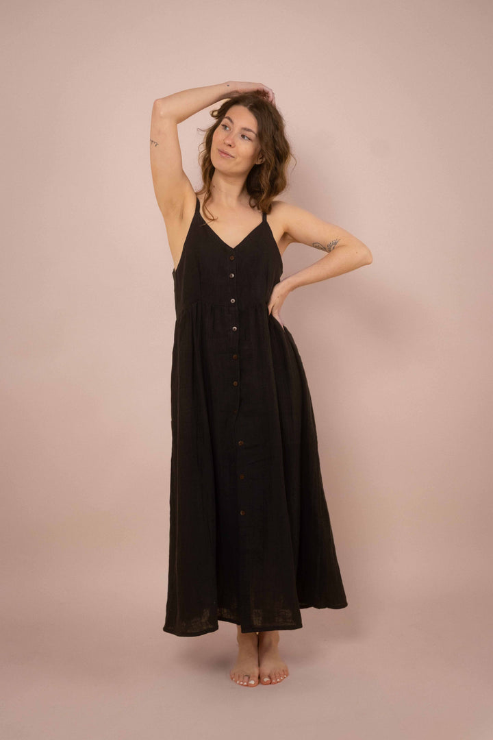 Ein elegantes schwarzes Maxikleid mit Knöpfen. das lange Trägerkleid hat einen V-Ausschnitt und ist minimalistisch gehalten. Vintagekleid. 