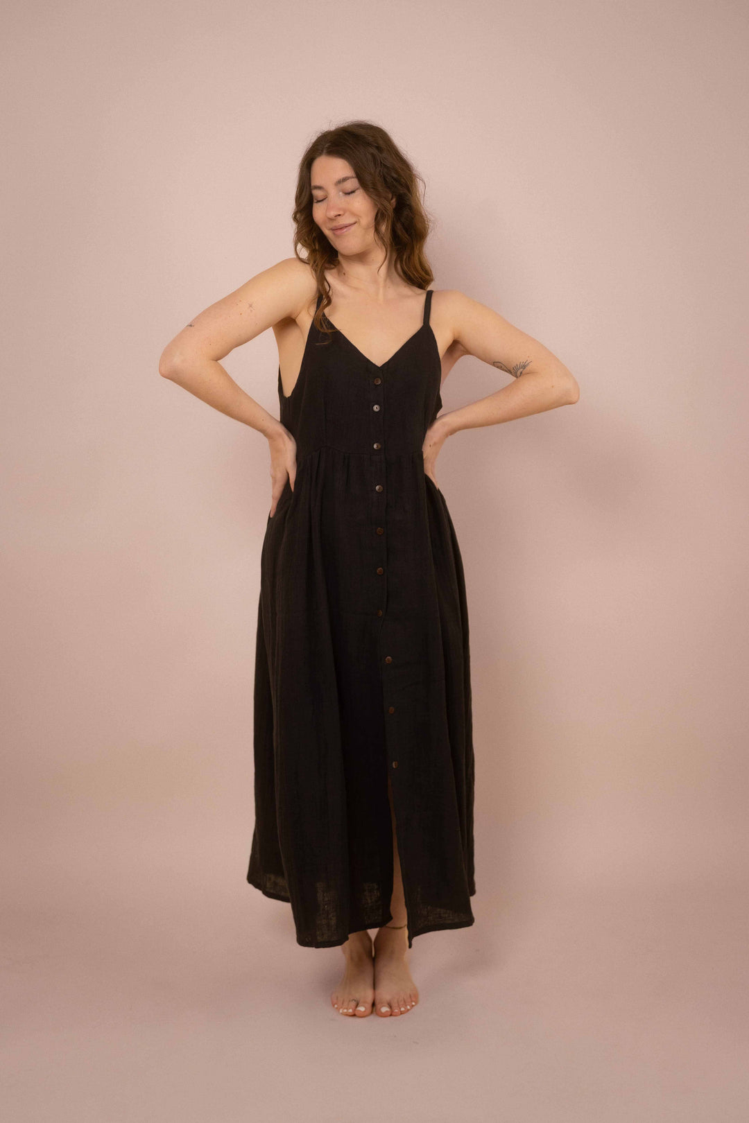Ein elegantes schwarzes Maxikleid mit Knöpfen. das lange Trägerkleid hat einen V-Ausschnitt und ist minimalistisch gehalten. Vintagekleid. 
