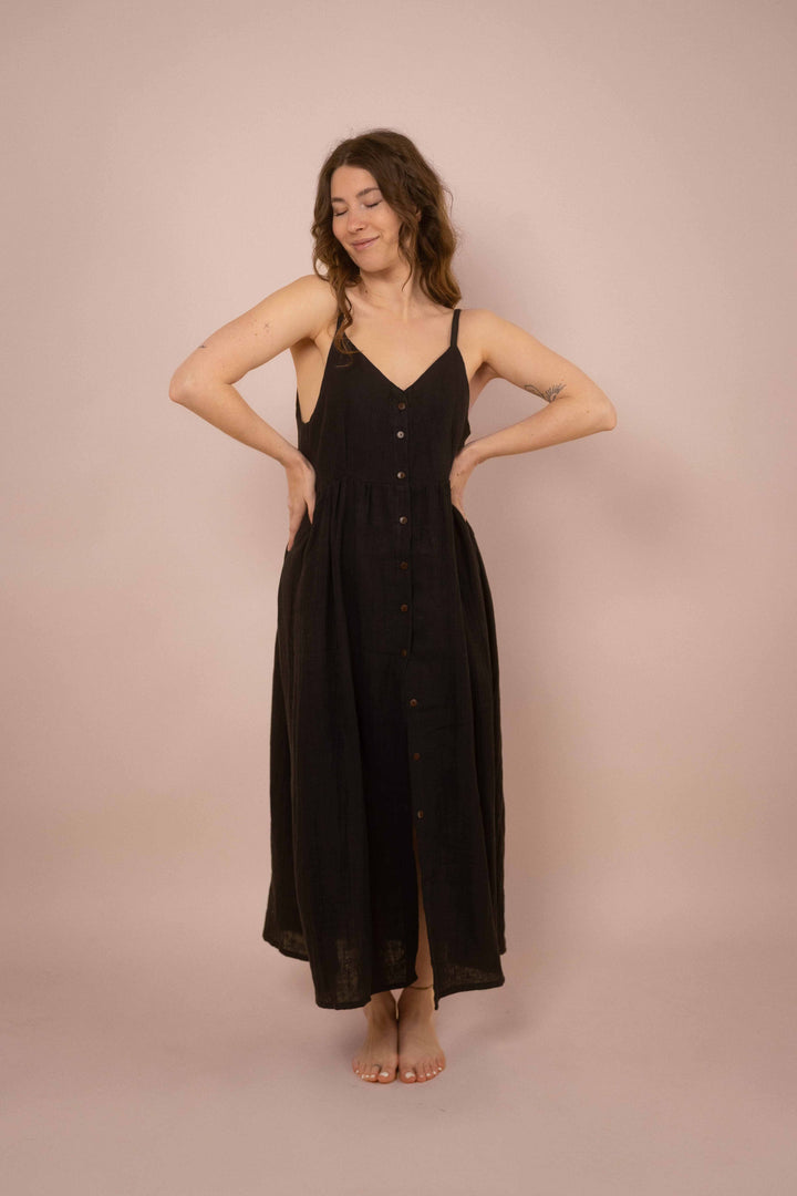 Ein elegantes schwarzes Maxikleid mit Knöpfen. das lange Trägerkleid hat einen V-Ausschnitt und ist minimalistisch gehalten. Vintagekleid. 
