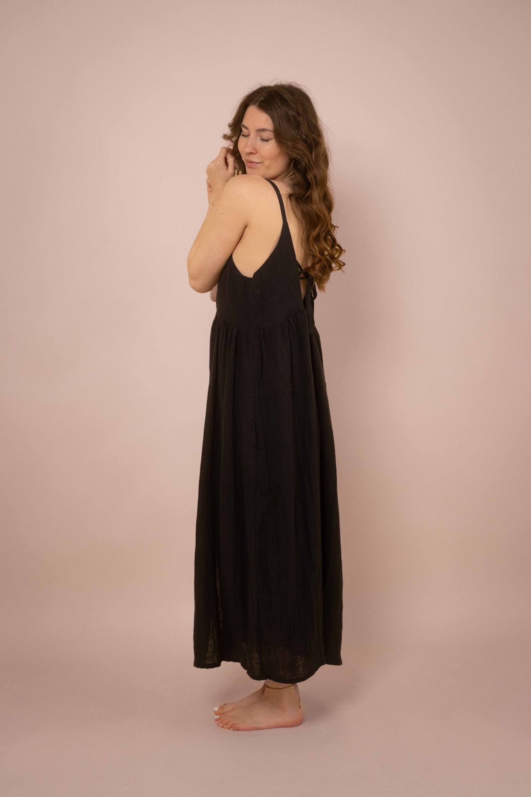 Ein elegantes schwarzes Maxikleid mit Knöpfen. das lange Trägerkleid hat einen V-Ausschnitt und ist minimalistisch gehalten. Vintagekleid. 