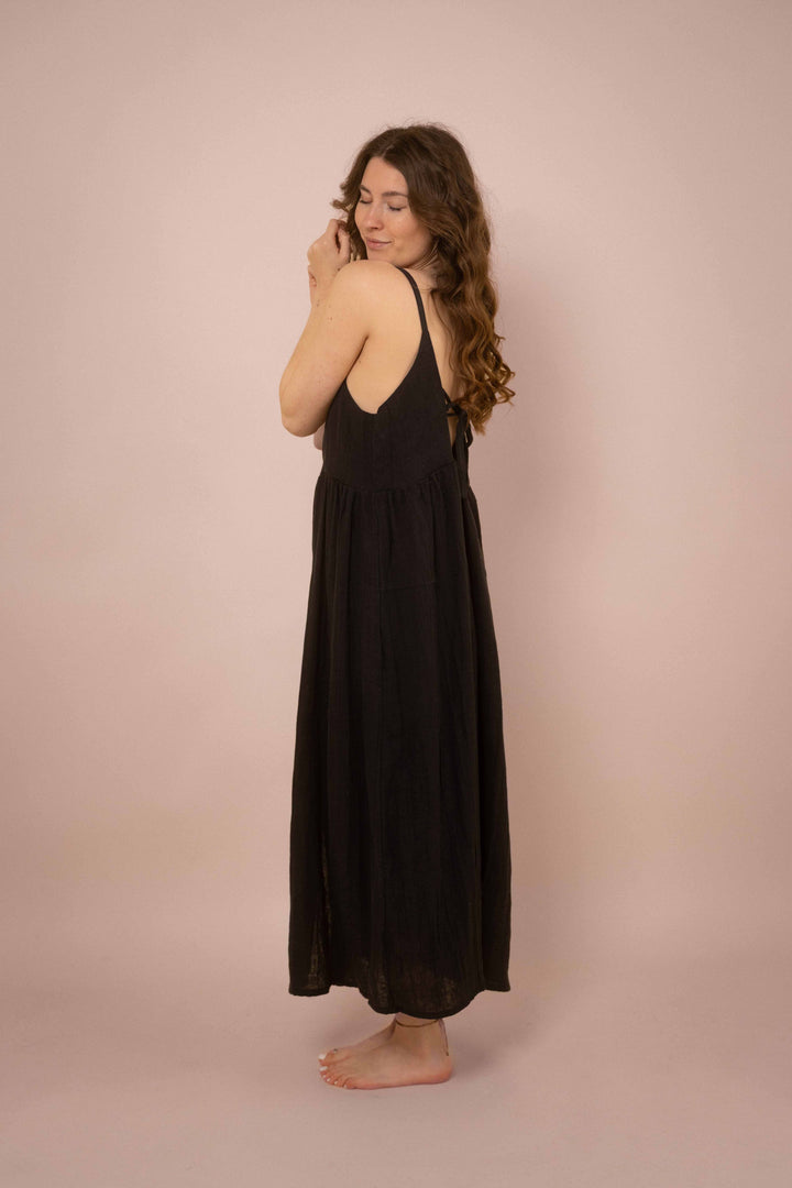 Ein elegantes schwarzes Maxikleid mit Knöpfen. das lange Trägerkleid hat einen V-Ausschnitt und ist minimalistisch gehalten. Vintagekleid. 