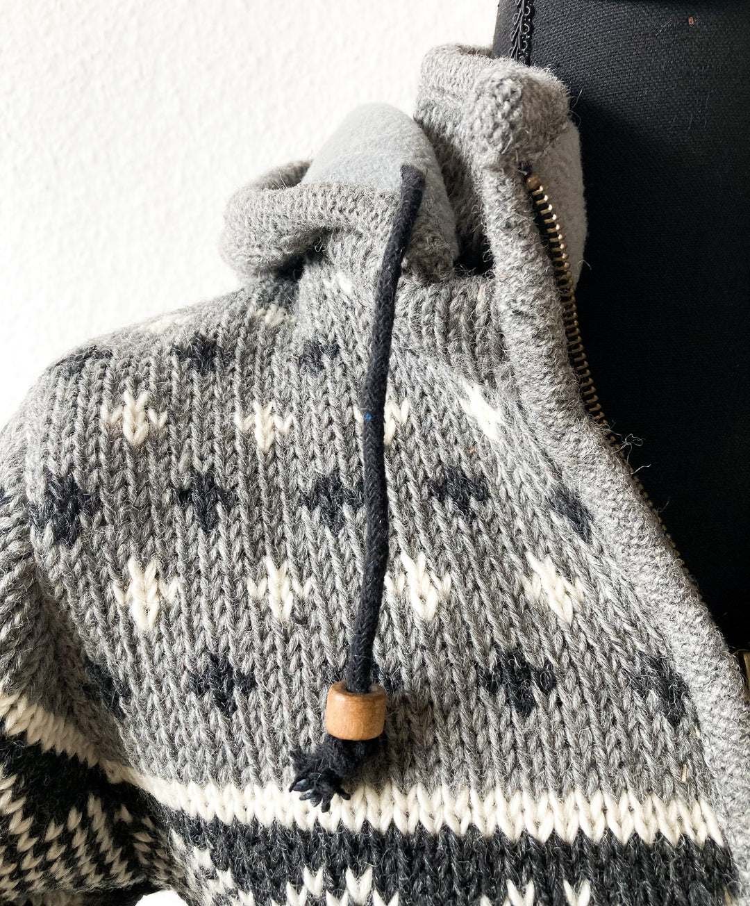 Gestrickte Jacke aus Wolle Grau Detailaufnahme Bändchen Kapuze